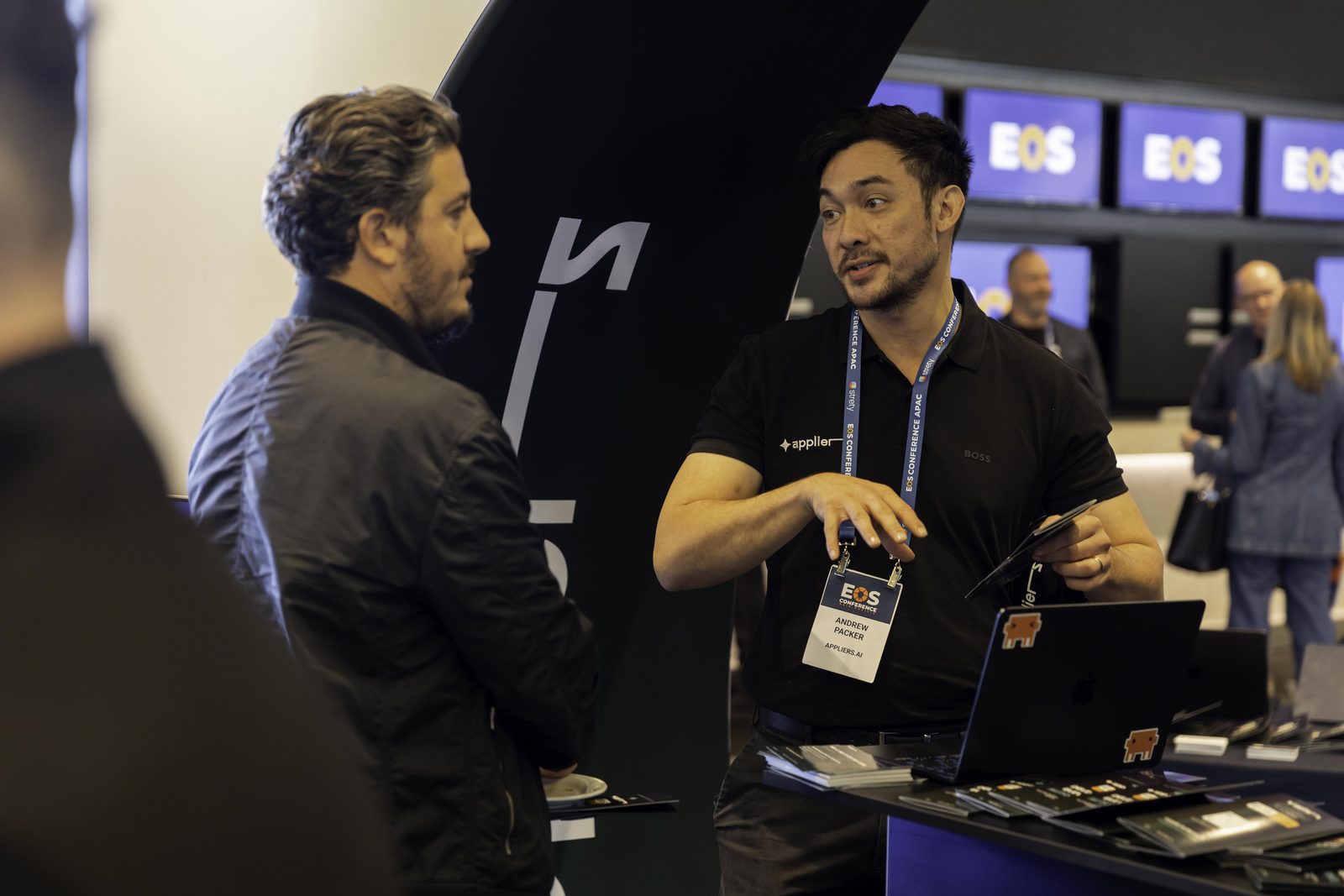 Two Appliers team members demonstrating on a laptop at the stand for a guest.
