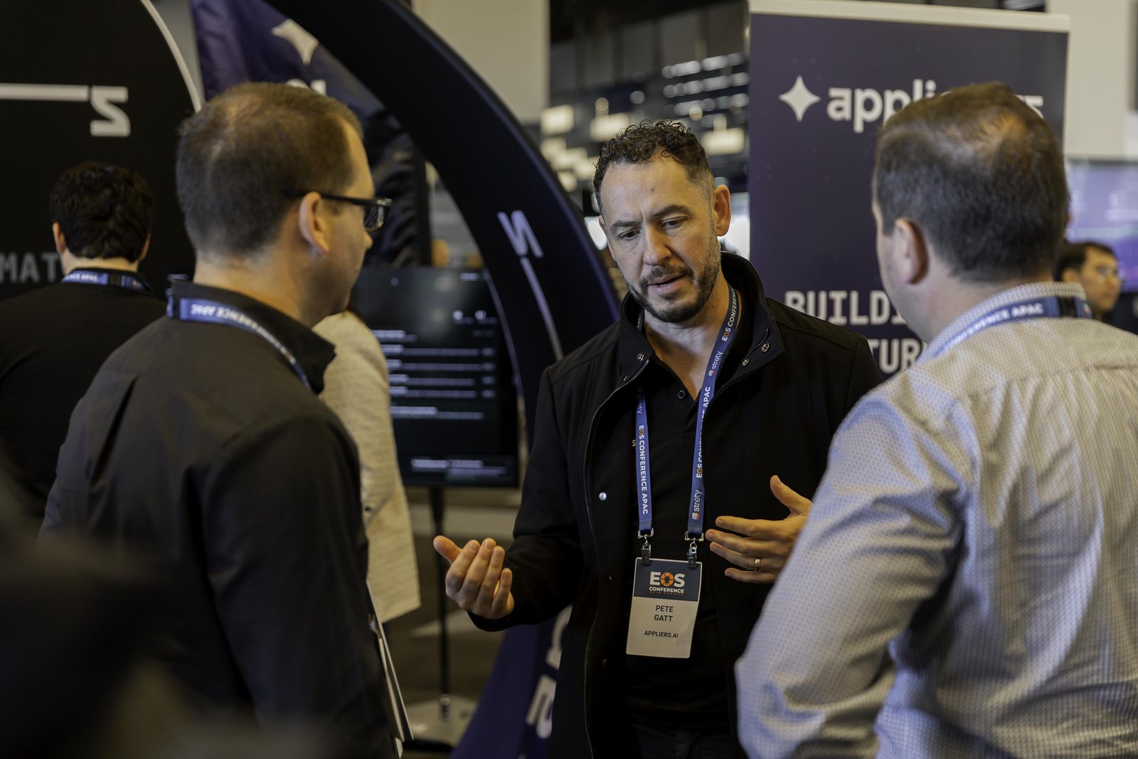 An Appliers team member in conversation with two business owners on the expo floor.