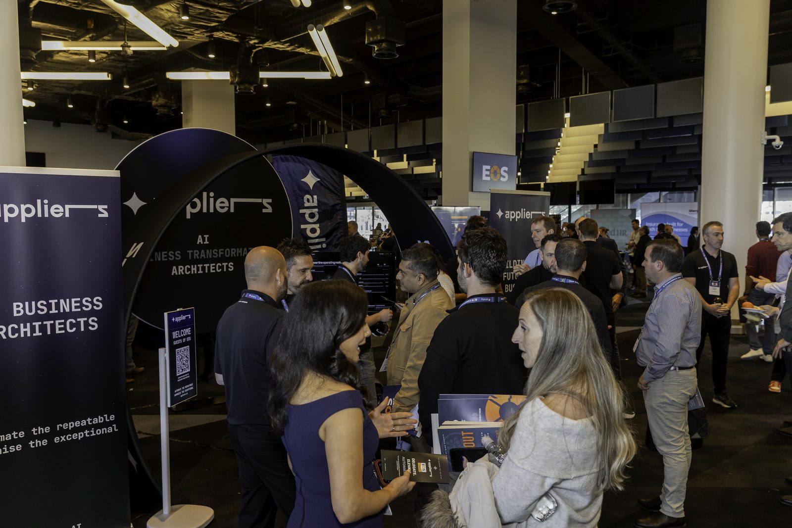 Conference guests gathered around the Appliers stand talking with the team during a break.