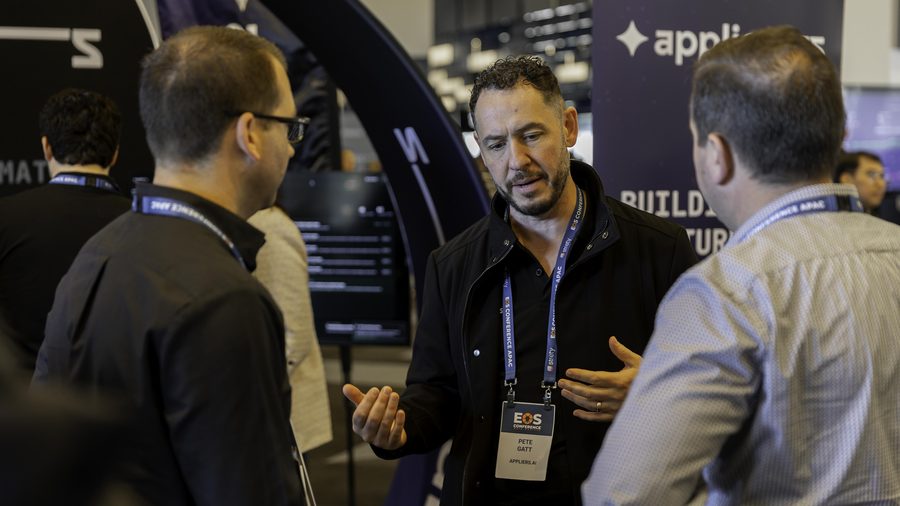 An Appliers team member talking through a process with two business owners at the stand.